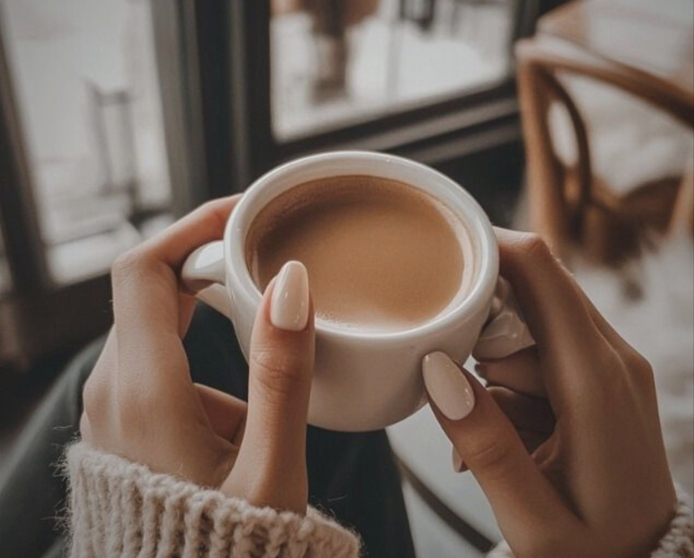 Person holding a cup of coffee with a blurred background and text overlay.