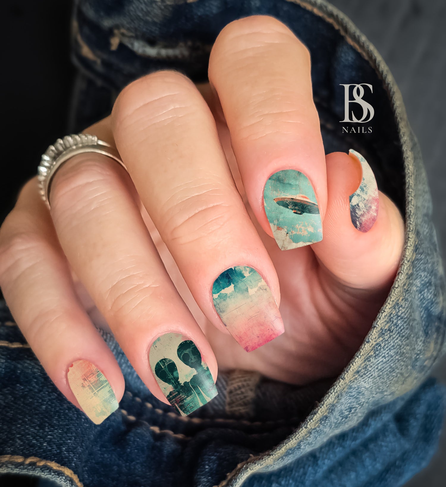 Retro Alien Nails with artistic design held by a person wearing denim jeans.