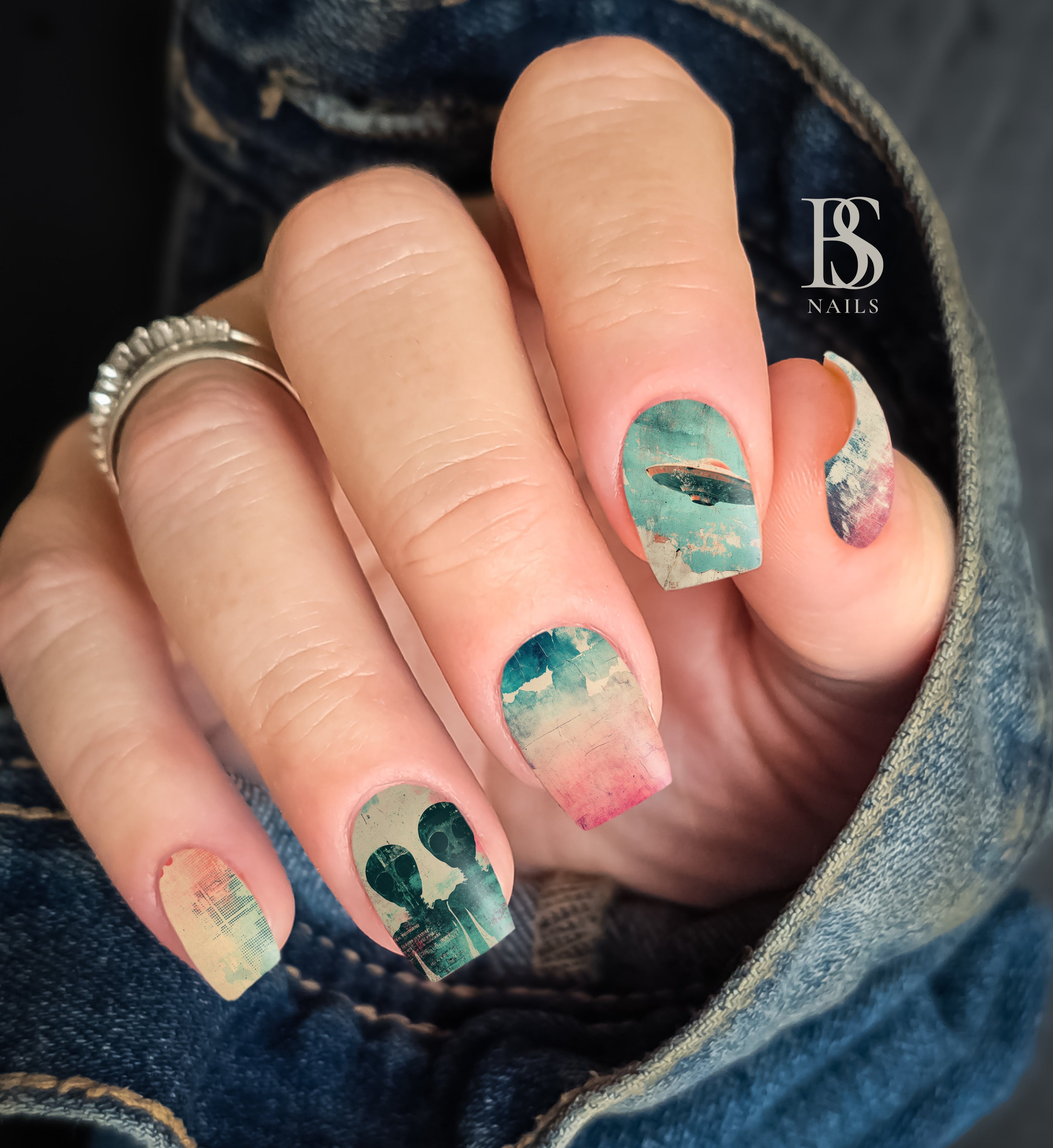 Retro Alien Nails with artistic design held by a person wearing denim jeans.